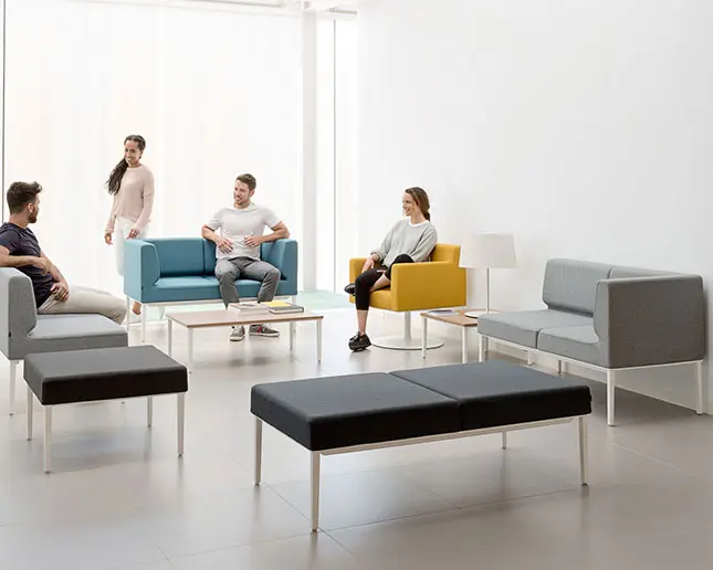 Sofás modulares Longo Actiu en gris y azul para oficinas colaborativas Grupo de personas conversando en sofás modulares Longo Actiu gris y azul en oficina moderna