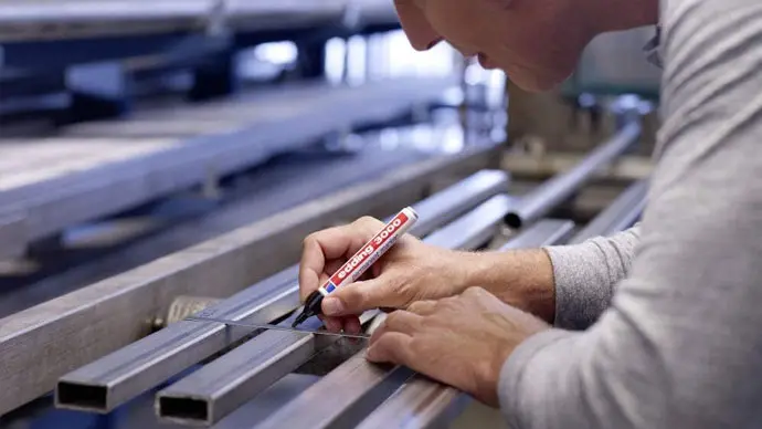 Fabricado con aluminio reciclado posconsumo (PCR), el cuerpo del Edding 3000 ofrece una estructura duradera y resistente a golpes y condiciones de trabajo intensas. Esta imagen ilustra perfectamente su uso en carpintería o construcción, donde la fiabilidad del rotulador es clave para marcar sobre madera o superficies irregulares.
