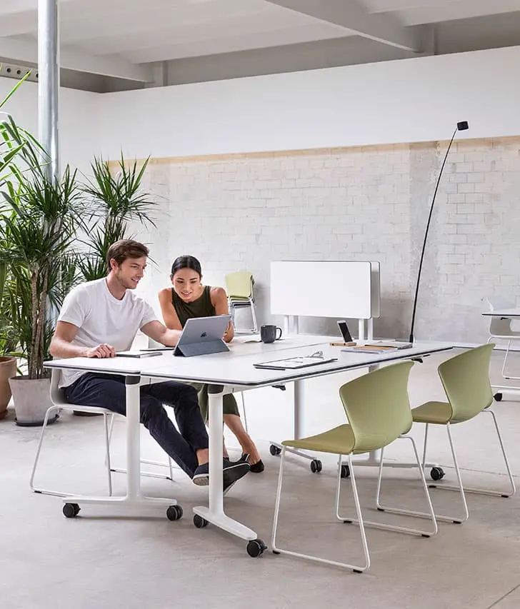 Hombre y mujer sentados en una silla y trabajando en una mesa de oficina con ruedas