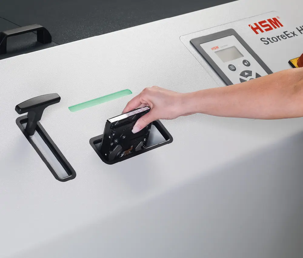 Alimentación de soportes en la destructora HSM HDS 150 Mano introduciendo un disco duro en la abertura de la HSM HDS 150